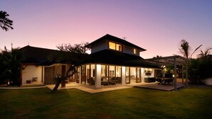 Una casa moderna con veranda vetrata, zona relax all'aperto coperta e prato curato.