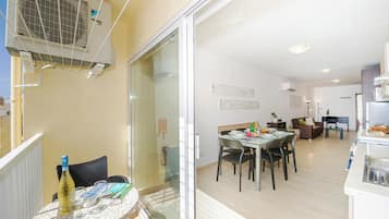Um apartamento moderno com área de jantar, cozinha e varanda com unidade de ar condicionado.