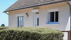 Ein zweistöckiges Haus mit Ziegeldach, zwei Fenstern im Erdgeschoss und einem kleinen Balkon.