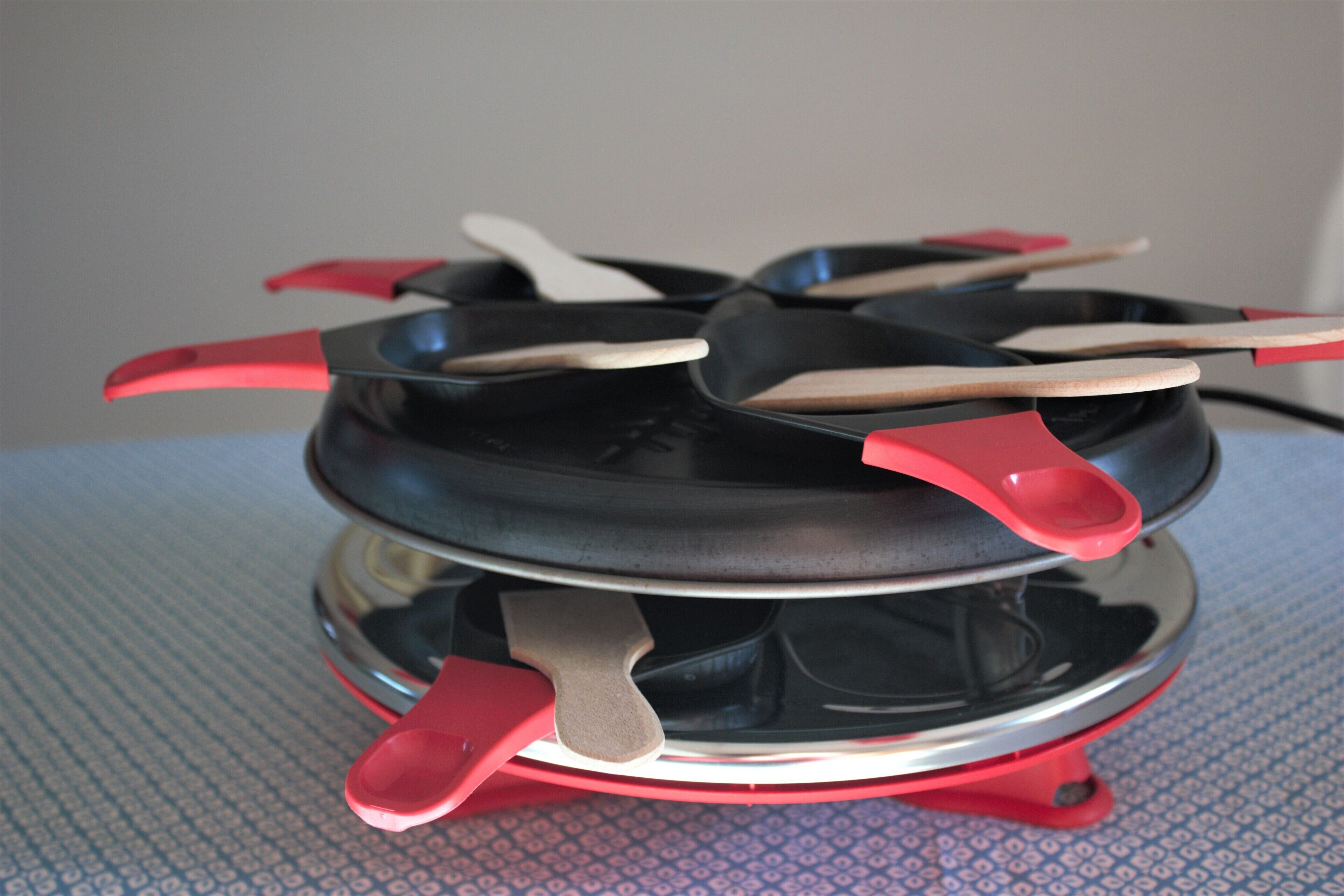 A portable electric stove with red handles and a black cooking surface.