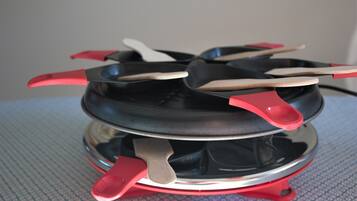 A portable electric stove with red handles and a black cooking surface.