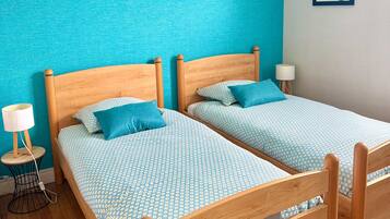 Una cama doble con una colcha estampada, una mesita de noche con una lámpara, y una pared con un cuadro enmarcado.
