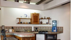 A kitchen with a central island, a built-in microwave, a water dispenser, and a ceiling fan. - One Bedroom Apt In The Heart Of Playa Only One Block to the Beach! (Playa del Carmen)