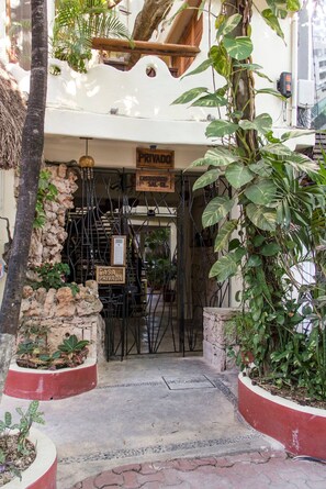 A private entrance with a sign, a stone wall, and potted plants.
