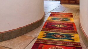 A hallway with a patterned rug, a wooden bench, and a door leading to an outdoor area. - One Bedroom Apt In The Heart Of Playa Only One Block to the Beach! (Playa del Carmen)