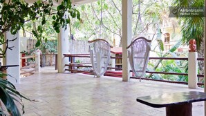 An outdoor covered patio with tiled flooring, two wicker chairs, and a table. - One Bedroom Apt In The Heart Of Playa Only One Block to the Beach! (Playa del Carmen)