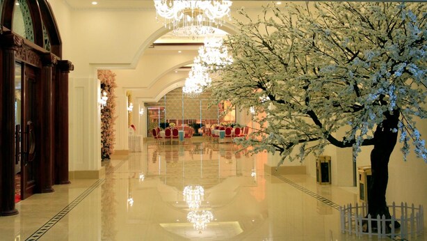 A spacious lobby with a polished floor, elegant chandeliers, and a large artificial cherry blossom tree. - Hai Yen Luxury Hotel (Cam Pha)