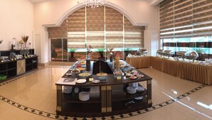 A buffet setup with multiple serving stations, a central buffet table, and a variety of food items. - Hai Yen Luxury Hotel (Cam Pha)