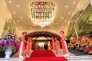 A grand entrance with a staircase, ornate decorations, and floral arrangements.