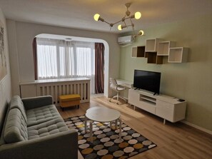 Una sala de estar moderna con un sofá, una mesa de centro, un televisor y un escritorio con una silla.