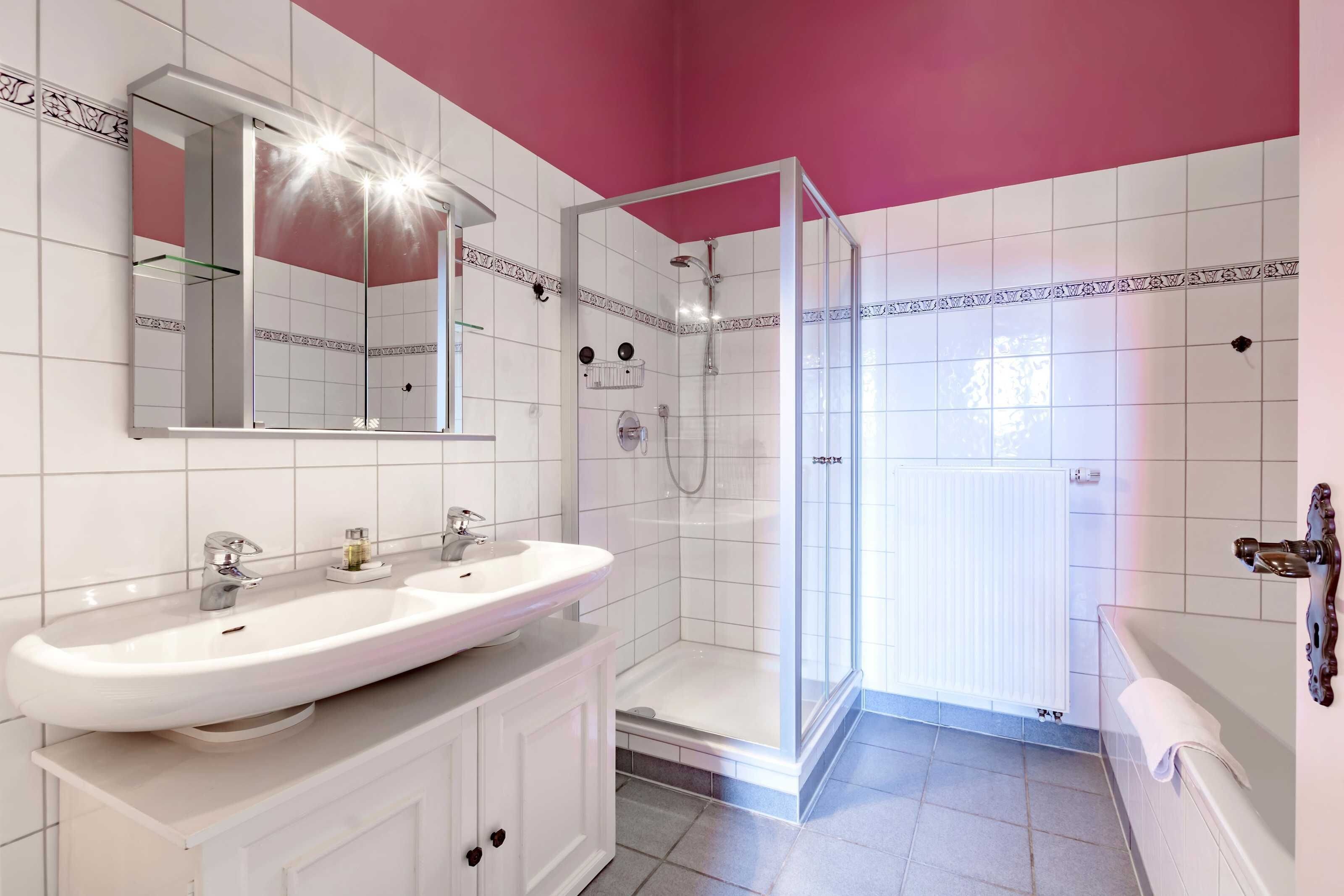 Ein Badezimmer mit Waschbecken, Spiegel, Dusche und Badewanne.