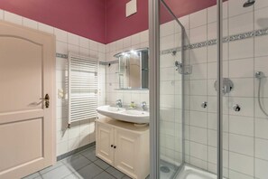 A bathroom with a glass shower enclosure, a white sink, and a mirror above it.