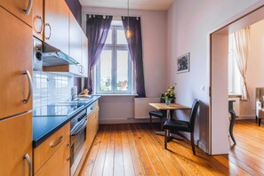 Una cocina compacta con armarios de madera, estufa y ventana con cortinas.