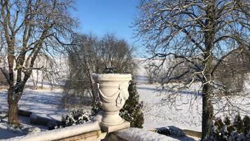 Ein mit Schnee bedeckter Garten mit einer weißen Vase auf einem Balustrade.