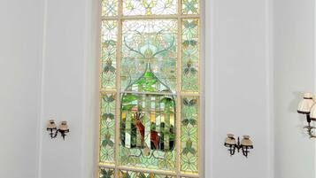 A room with a stained glass window, white walls, and a black bench.