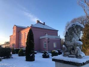 Un bâtiment rose avec une statue recouverte de neige au premier plan.
