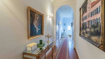 A hallway with a red carpet, a framed painting, a candelabra, and a mirror.