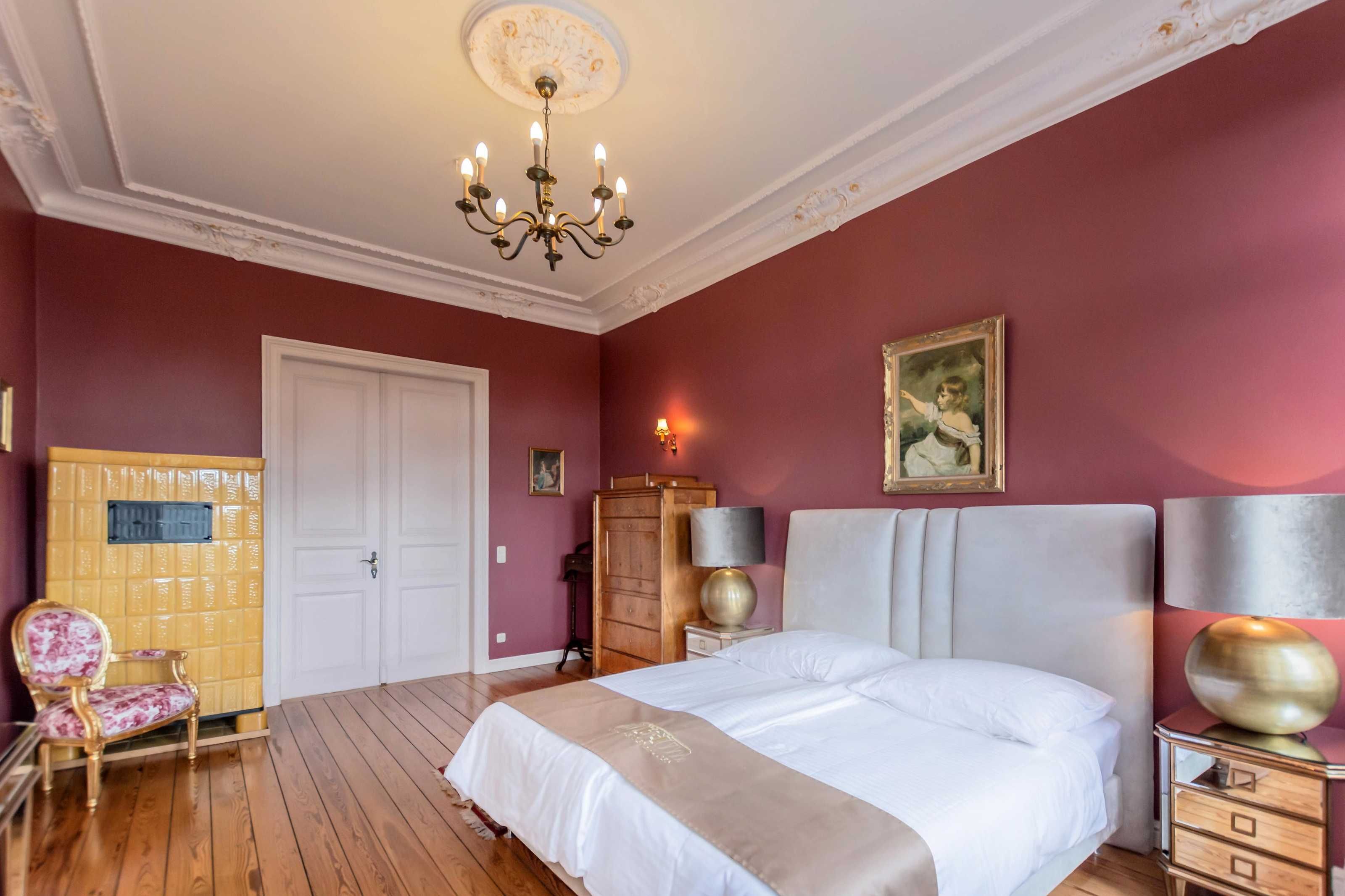 Ein Schlafzimmer mit einem großen Bett, einer Deckenleuchte, einem Kleiderschrank und einem Sessel.