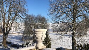 Un jardín cubierto de nieve con una urna blanca en un balcón.