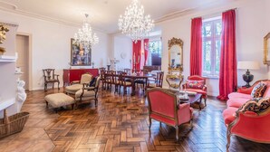 Una habitación con suelo de espiga, un comedor con mesa y sillas rojas, y un sofá rojo con cojines estampados.