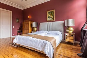 A bedroom with a large bed, two bedside lamps, a wooden nightstand, a wardrobe, and a painting on the wall. - Zimmer Ludwigslust - Schlosshotel Groß Köthel (Hohen-Demzin)