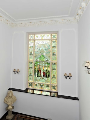 Una habitación con una ventana de vitral, paredes blancas y un banco negro.