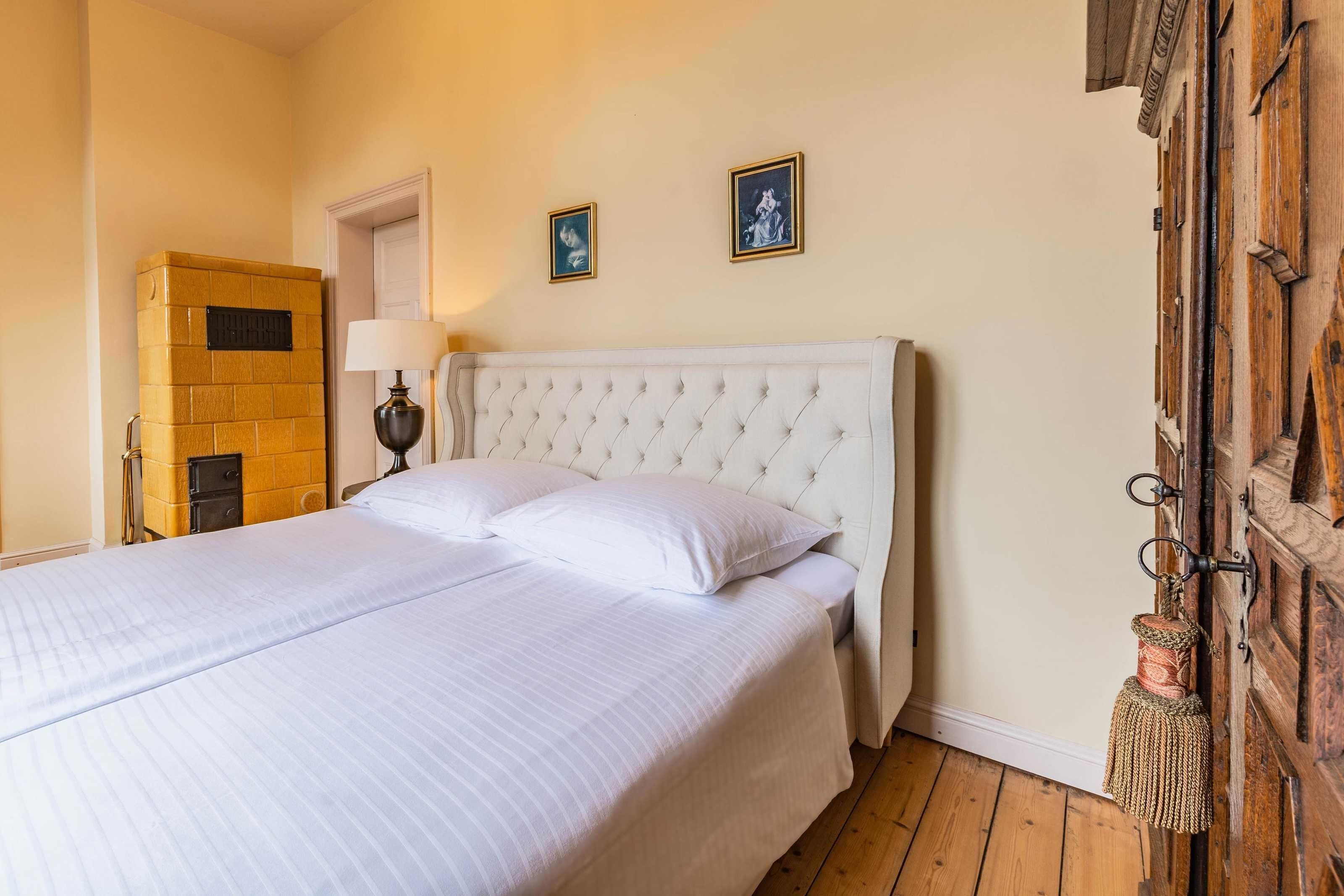 A bed with a white headboard, a wooden cabinet, and a door with a rustic design.