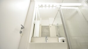 A bathroom with a white sink, a mirror, and a glass shower enclosure. - Candy Studio - Cismigiu Gardens - Quiet Room - Open Kitchen -smart Tv (Bucharest)