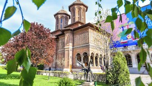 A historic building with two towers, surrounded by a well-maintained garden and a statue. - Candy Studio - Cismigiu Gardens - Quiet Room - Open Kitchen -smart Tv (Bucharest)