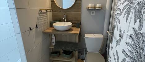 A compact bathroom with a round mirror, a white sink, and a toilet.