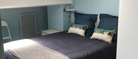 A bedroom with a bed, a desk, and a chair.