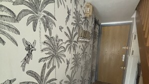 Een gang met houten vloer en een muur met een tropisch bladpatroon.