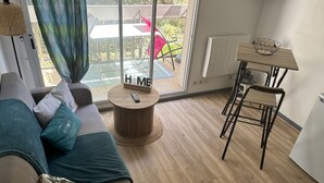 Een moderne woonkamer met een bank, een ronde houten salontafel, een eettafel met stoelen en uitzicht op de omgeving.