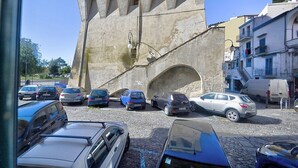 Un aparcamiento con varios coches y una gran estructura de piedra con un arco.