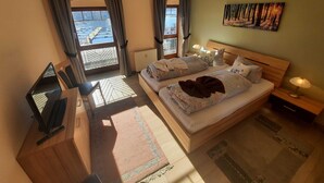Ein Hotelzimmer mit Bett, Schreibtisch, Stuhl, Fernseher und einem Fenster mit Vorhängen.