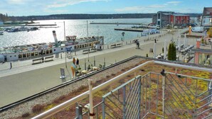 Eine Uferpromenade mit Anlegestelle, Booten und einem Gebäude mit roter Fassade.