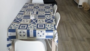 A dining area with a table set for two, a sofa, and a television on a stand. - SeaHouse (Torre Vado marina di morciano di leuca)
