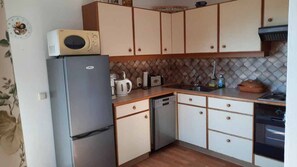 Eine kompakte Küche mit Kühlschrank, Mikrowelle, Toaster und Geschirrspüler.