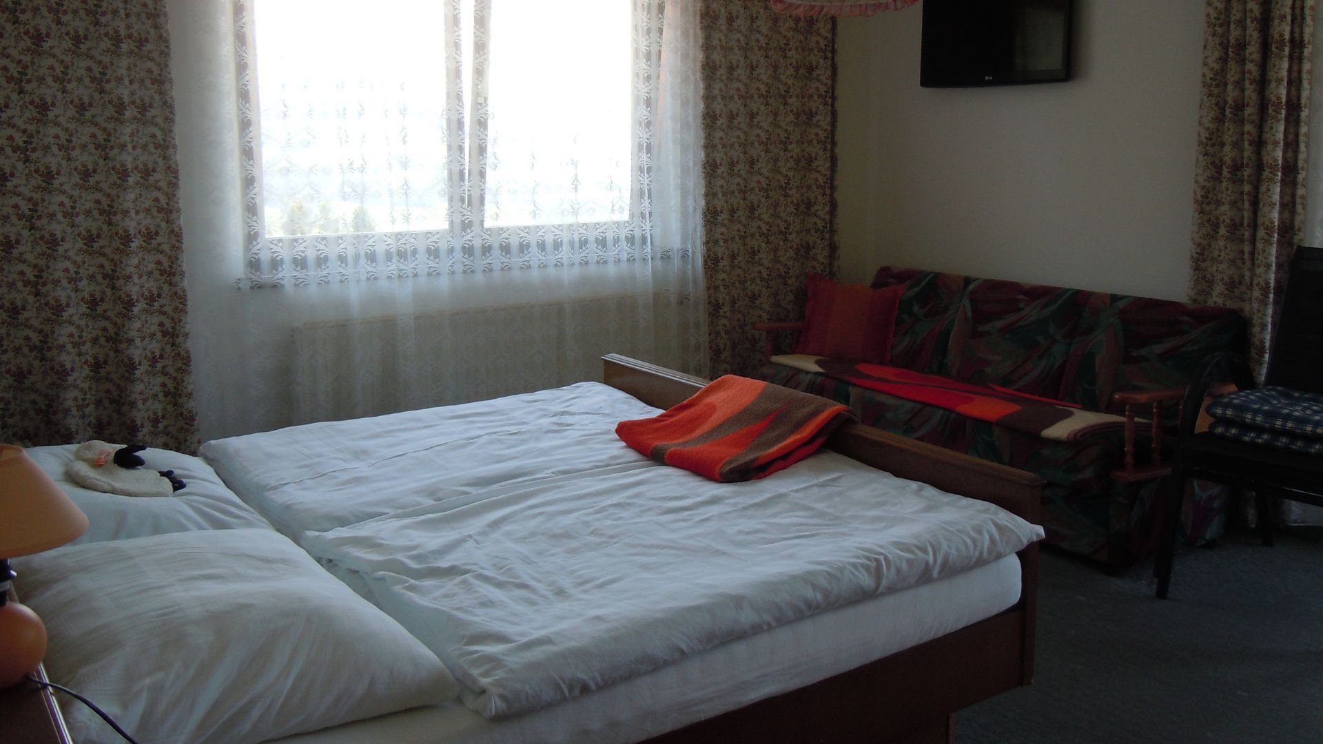Een hotelkamer met een bed, een bank, een televisie en een raam met gordijnen.