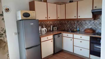 A compact kitchen with a refrigerator, microwave, toaster, and dishwasher.