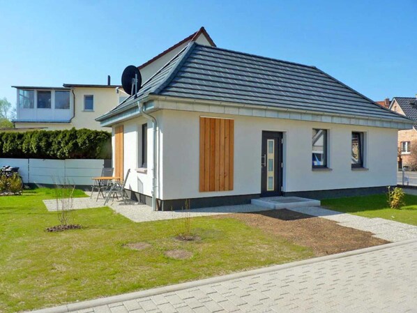 Ett modernt enplanshus med ett sluttande tak, en liten veranda och en välskött gräsmatta.
