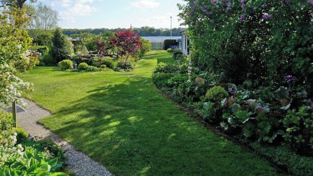 Un jardin bien entretenu, avec une grande variété de plantes et un chemin bien défini menant à un bâtiment.