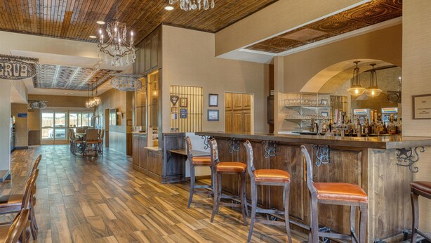 A bar area with wooden flooring, bar stools, and a bar counter. - Best Western Bandera Suites & Saloon (Bandera)