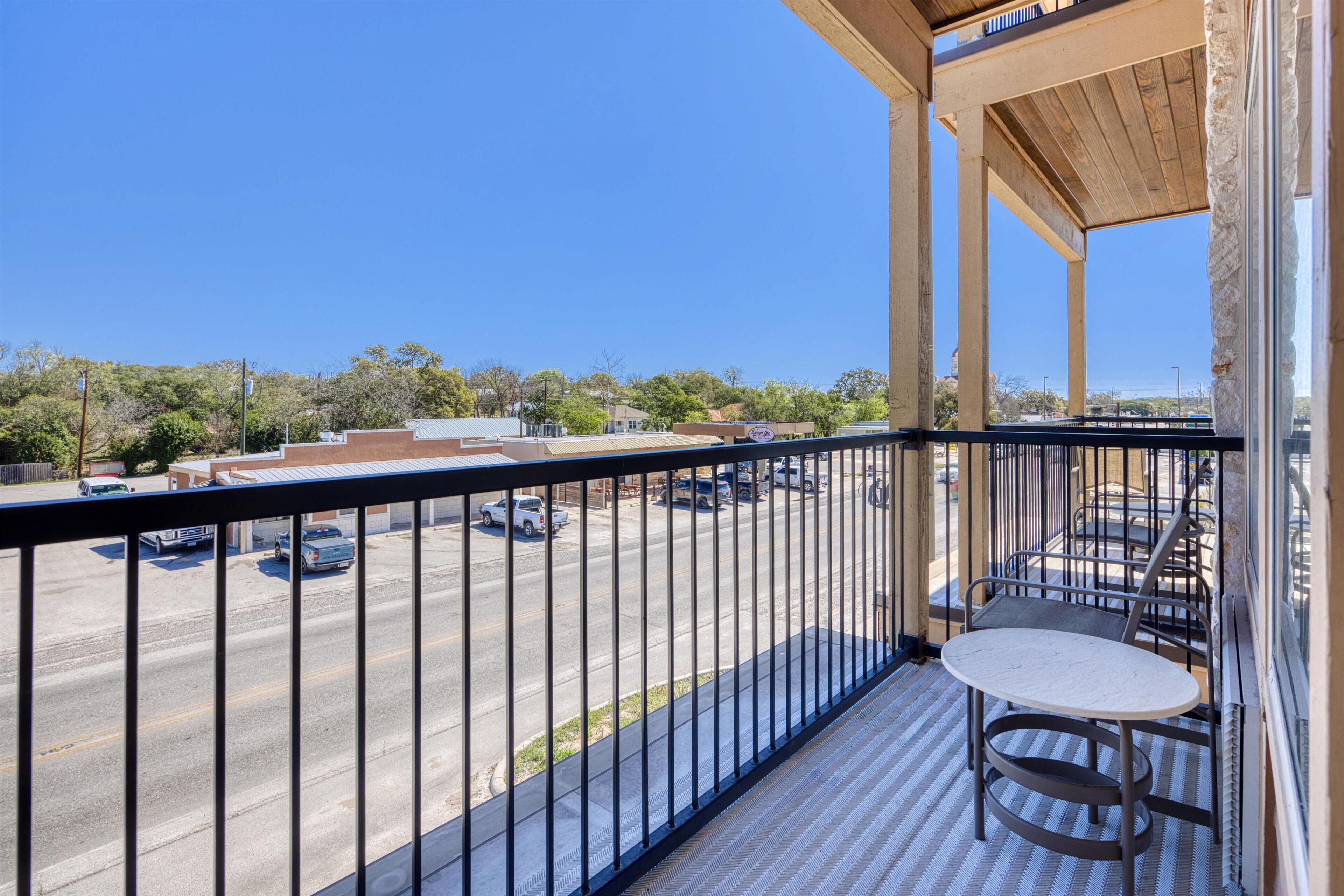 A balcony with a view of a parking lot and buildings.