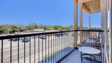 A balcony with a view of a parking lot and buildings.