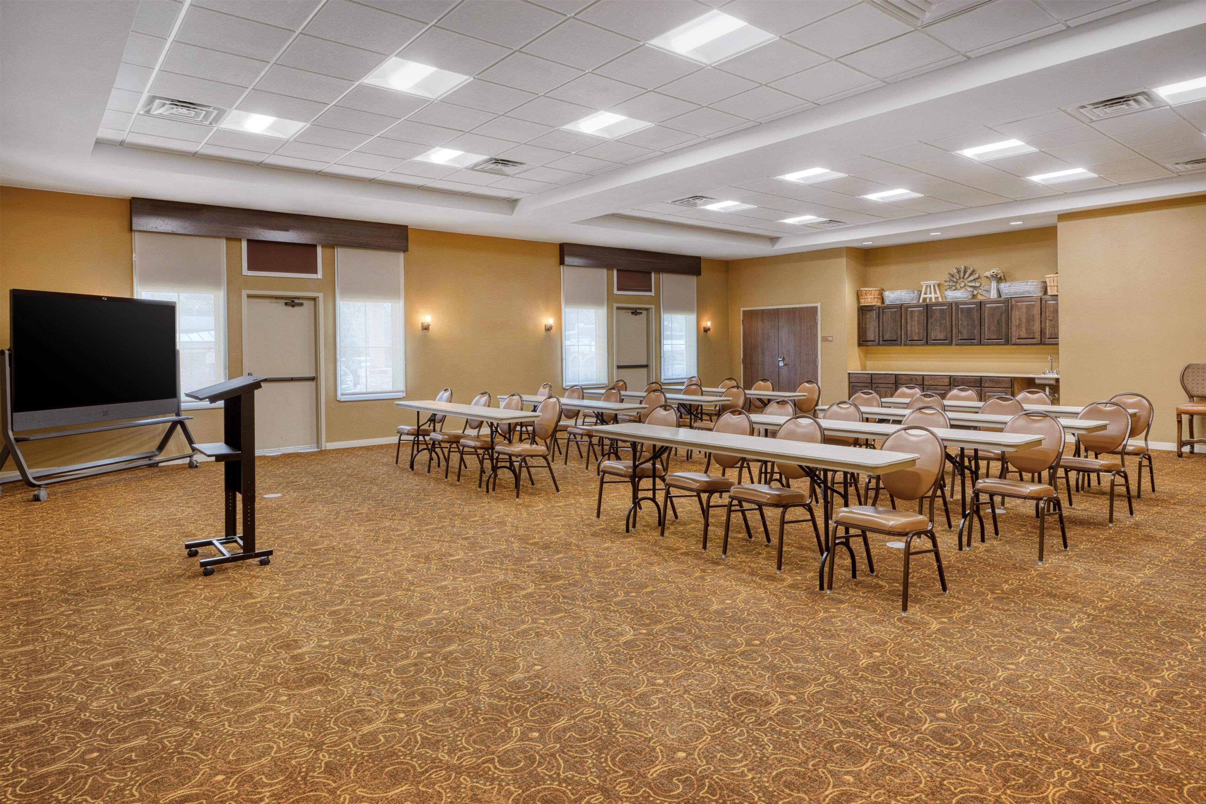 A conference room with a long table, chairs, a projector, and a carpeted floor.