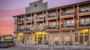 A multi-story hotel with a 'Best Western' sign, a parking lot, and a 'Dollar General' store across the street. - Best Western Bandera Suites & Saloon (Bandera)