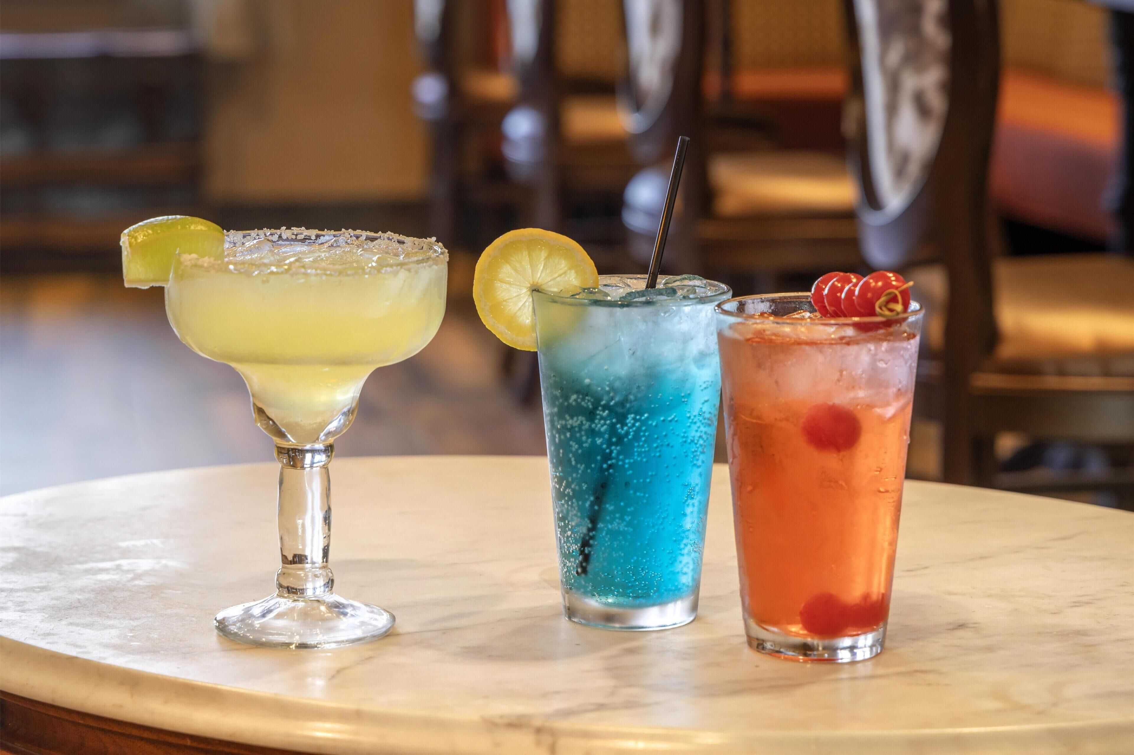 Three cocktails on a marble table.
