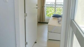 A narrow hallway leading to a room with a bed, a window with curtains, and a hanging light fixture. - Pacio Nijo (Kyoto)