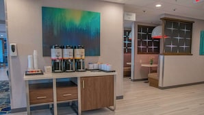 A hotel reception area with a coffee station, a painting, and a sign for the elevator. - Hampton Inn Wabash (Wabash)